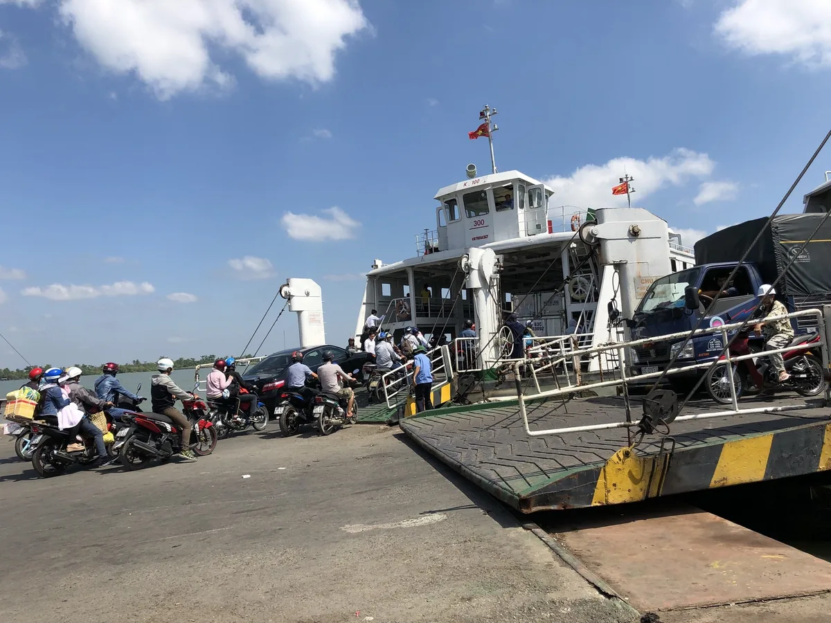 Xe máy và ô tô xếp hàng lên phà sông tại bến ở thành phố Vĩnh Long.