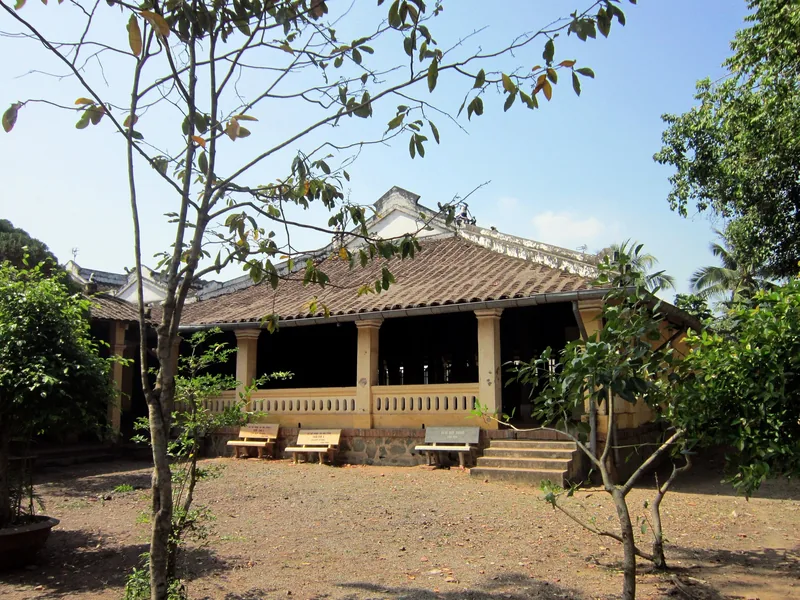 Ngôi nhà cổ mái ngói với hàng cột hiên và khu vườn ở Đồng bằng sông Cửu Long, Việt Nam.