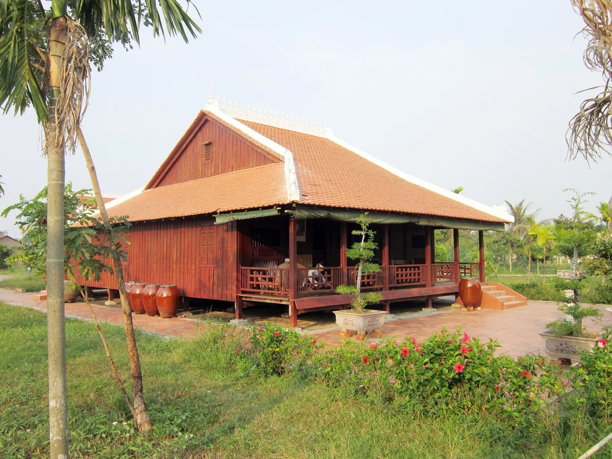 Một ngôi nhà sàn gỗ truyền thống với mái ngói đỏ nằm giữa khu vườn ở Đồng bằng sông Cửu Long.