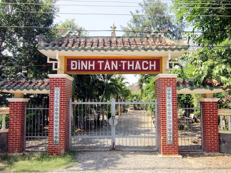 Cổng ngói cổ kính với trụ gạch đỏ dẫn vào đình Tân Thạch ở vùng Đồng bằng sông Cửu Long.