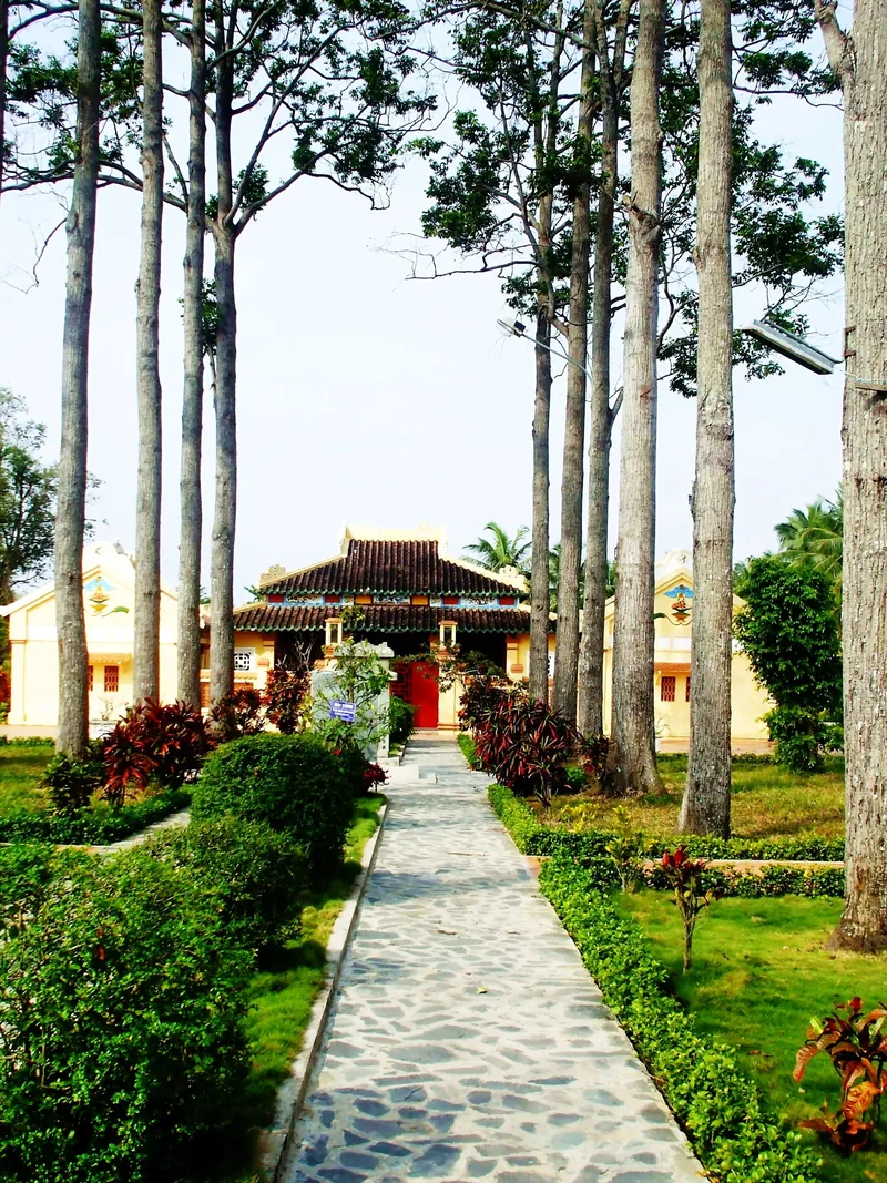 Con đường lát đá rợp bóng cây cao dẫn đến ngôi nhà cổ mái ngói đỏ tại Văn Thánh Miếu, Vĩnh Long.